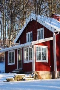 una casa roja con nieve en el techo en Anfasteröd Gårdsvik - Grindstugan, en Ljungskile