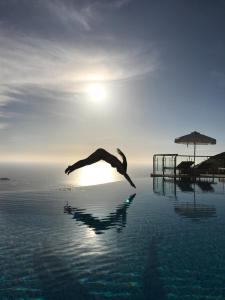 a person jumping into the water in a pool at Petani Bay Hotel - Adults Only in Vóvikes