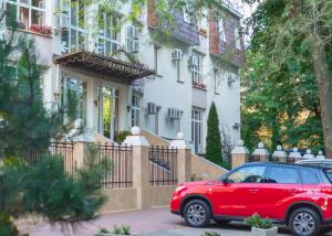 un coche rojo estacionado frente a una casa en Lermontovskiy Hotel, en Odessa