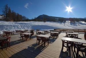 une terrasse avec des tables et des chaises dans la neige dans l'établissement Hotel Spa L'Equipe, à Molines-en-Queyras