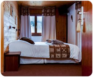 a bedroom with a bed and a window at Hotel Spa L'Equipe in Molines-en-Queyras