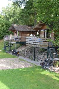 une cabane dans les arbres avec une terrasse et des vélos garés à l'extérieur dans l'établissement Camping Hitjesvijver, à Heerlen