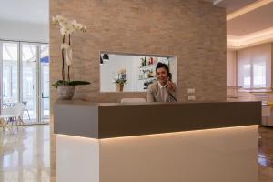 a man talking on a cell phone at a reception desk at Hotel Dolomiti in Caorle