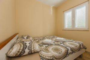 een slaapkamer met een bed met een deken en een raam bij Villa Joma 2 in Trogir