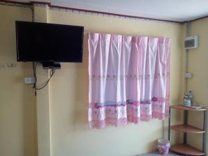 a room with a pink curtain and a tv at Lung Teeb Paradise Chao Lao Resort in Chao Lao Beach