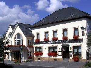 a white building with red flowers in the windows at Hotel Landgasthof Gemmer in Rettert