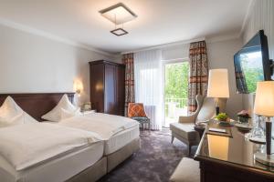 バート・ノイェンアール・アールヴァイラーにあるPrivat-Hotel Villa Auroraのベッドとリビングルームが備わるホテルルームです。