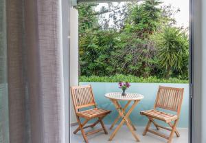 - un balcon avec une fenêtre doté de 2 chaises et d'une table dans l'établissement Forum Suites, à Kato Daratso