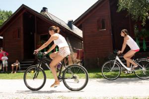 two women riding bikes in front of a house at Camping Era Yerla D'arties in Arties