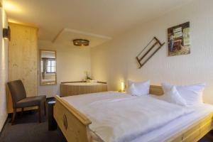 a bedroom with a large white bed and a chair at Burghotel Stolpen in Stolpen