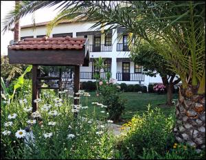 a garden in front of a white house with flowers at Villa Rhapsody Pension in Kayakoy
