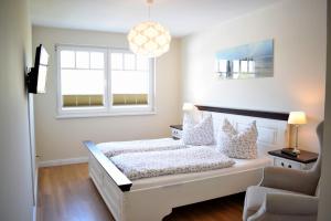 ein weißes Schlafzimmer mit einem Bett und einem Fenster in der Unterkunft Villa Ocean Place in Haffkrug