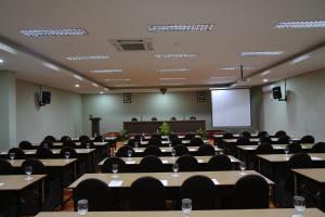 a conference room with tables and chairs and a screen at Samara Resort in Batu