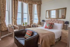 a bedroom with a bed and a chair and windows at Panorama in Tenby