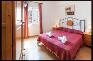 La Playa de la Torre de PilesにあるOdiseaのベッドルーム1室(赤いベッド1台、白いタオル2枚付)