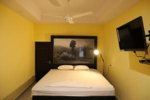 1 dormitorio con 1 cama y TV de pantalla plana en AIRCO Le-Grand Inn, en Thiruvalla