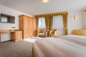 a bedroom with a bed and a dresser at Hotel Maria in Ortisei