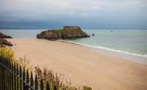 a beach with a castle in the water at Panorama in Tenby