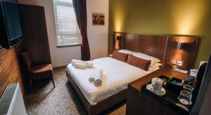 a hotel room with a large bed and a desk at The Commercial Hotel in Wishaw