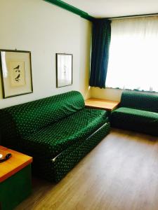 マドンナ・ディ・カンピリオにあるResidence Hotel Sport Campiglioのリビングルーム(緑のソファ、窓付)