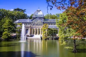 a conservatory in a park with a pond and a fountain at BOOKINGHAM ★Apartaments & Suites in Madrid