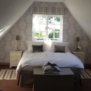 een slaapkamer met een wit bed met een raam bij Gardeners Cottage in Crudwell