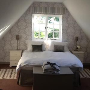 a bedroom with a white bed with a window at Gardeners Cottage in Crudwell