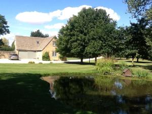 a house with a pond in front of a house at Gardeners Cottage in Crudwell