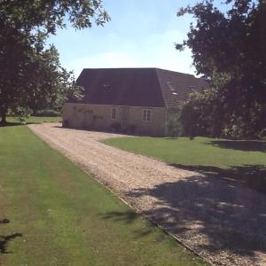 a barn with a stone road next to a field at Gardeners Cottage in Crudwell