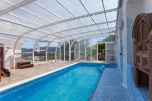an indoor swimming pool with a glass ceiling and a swimming poolvisor at Llumicel in Ador