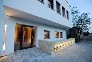 a white house with a stone wall and a door at Genuss Am Hof in Halbturn