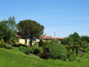 a house on a green hill with trees and bushes at Au Moulié in Blousson-Sérian