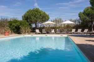 - une piscine avec des chaises longues et des parasols dans l'établissement Éco-Domaine La Fontaine Hotel Spa & Résidence, à Pornic