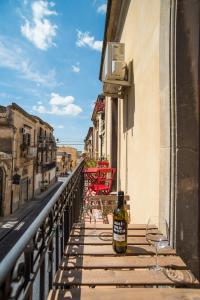 Una botella de vino sentada en una mesa en un balcón en Casa Lina, en Noto