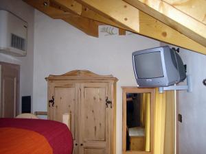 una TV sopra un comò in una camera da letto di Garni La Genziana a Temù