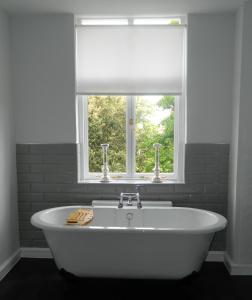 a white bath tub in a bathroom with a window at Birchover Bridgford Hall in Nottingham