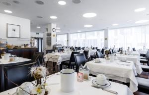 uma sala de jantar com mesas brancas e cadeiras pretas em ABC Swiss Quality Hotel em Chur