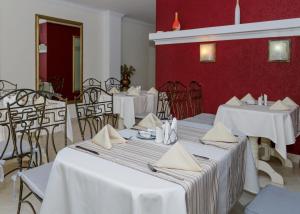 a restaurant with white tables and chairs and red walls at Lermontovskiy Hotel in Odesa