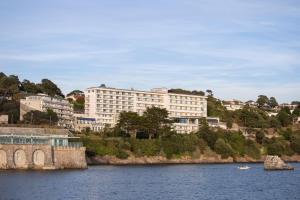 een groot gebouw op een heuvel naast een waterlichaam bij The Imperial Torquay in Torquay