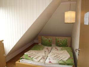 ein Bett mit grünen Decken und Kissen im Dachgeschoss in der Unterkunft Haus Ostseeatoll in Warnemünde