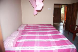 Cama en habitación con manta rosa y morada en Kalpitiya Guest House, en Kalpitiya
