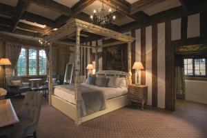 a bedroom with a large bed and a chandelier at Fawsley Hall Hotel in Daventry