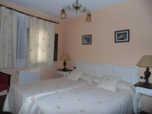 a bedroom with a bed with white sheets and a window at Apartamentos Rurales La Muralla II in Cañete