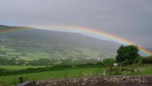 a rainbow over a green field with a hill at The Kestrel B&B in Crickhowell
