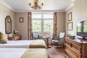 a hotel room with a bed and a tv and a table at The Imperial Torquay in Torquay