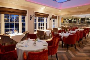a restaurant with white tables and red chairs at Sir Christopher Wren Hotel in Windsor