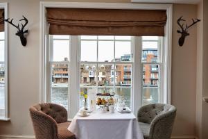 a table with chairs in front of a large window at Sir Christopher Wren Hotel in Windsor