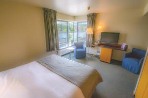 una camera d'albergo con letto, scrivania e TV di Hotel Sirius a Huy