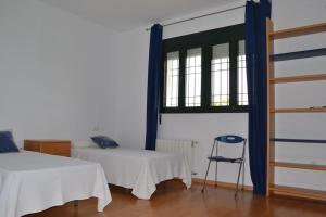 エル・プエルト・デ・サンタマリアにあるVilla las Redesのベッド2台、椅子、窓が備わる客室です。