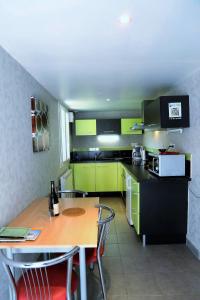 a kitchen with a wooden table and green cabinets at Gîte dans les Alpes Mancelles in Gesnes-le-Gandelin
